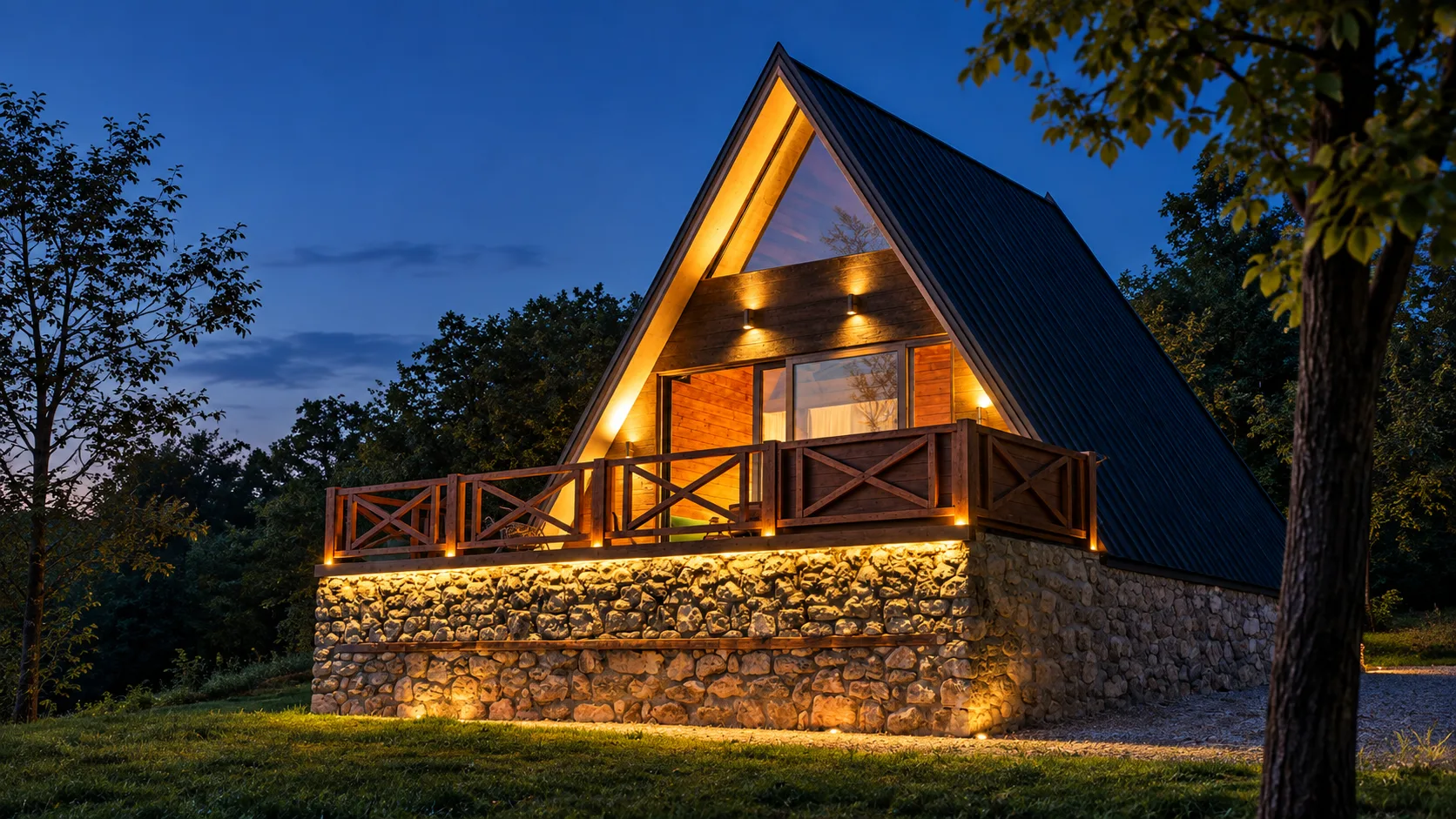 A House & Spa – A-frame cottage at night, lit terrace and stone base